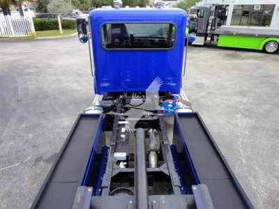 Blue Peterbilt 337 cab over truck seen from behind, with chassis and fifth wheel area visible and two long black side steps.