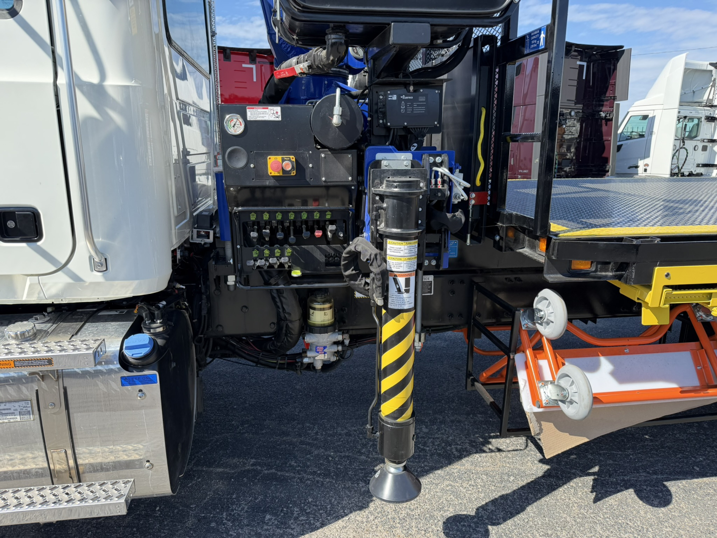 Mack GR64F crane truck rear showing hydraulic stabilizer leg extended and control panel with gauges.
