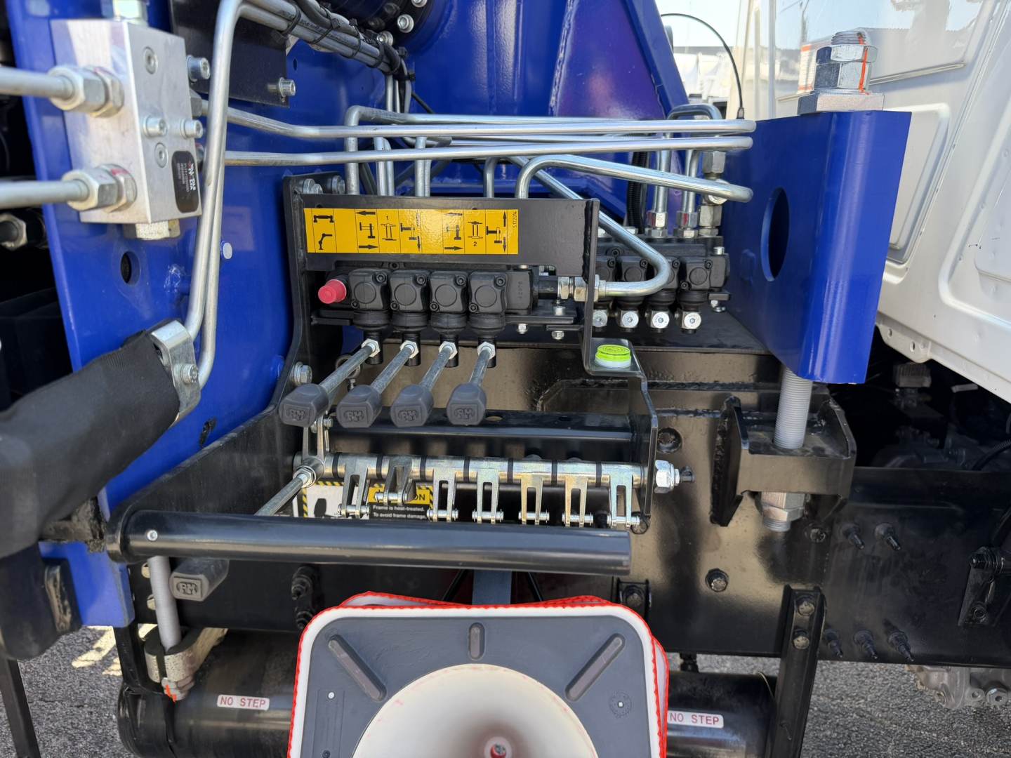 Crane truck hydraulic controls panel with levers and yellow label in Mack GR64F cabin area view.