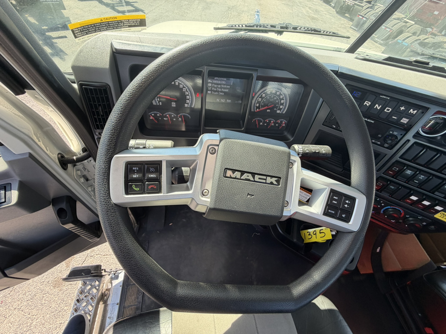 Mack GR64F truck cab interior steering wheel and dashboard view showing Mack emblem on the center and controls.