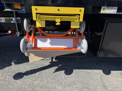 Mack GR64F truck crane attachment with yellow mounting bracket and orange stability components visible.