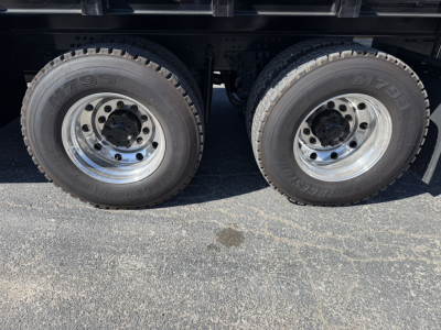 Dual rear axles with M60 tires and chrome wheels under a Mack GR64F crane truck showing tire treads and wheel hubs.