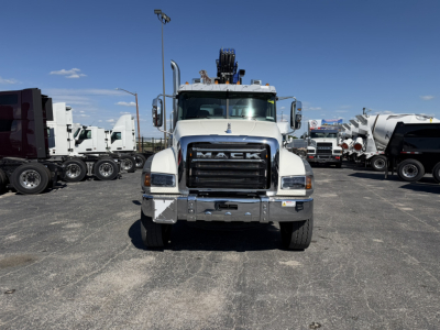 Front view of a white Mack GR64F heavy-duty truck with a prominent grille, bumper, and crane equipment on top.