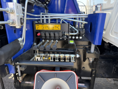 Crane truck hydraulic controls panel with levers and yellow label in Mack GR64F cabin area view.