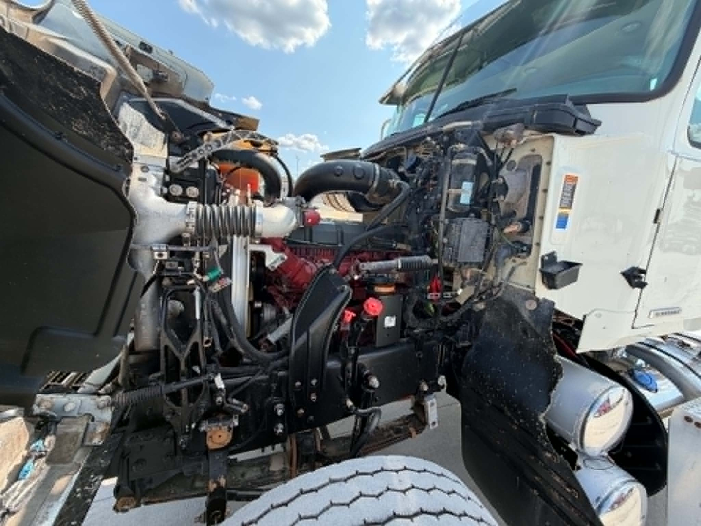 Truck engine bay of a 2019 Mack CHU613 front view showing exposed engine components and piping.