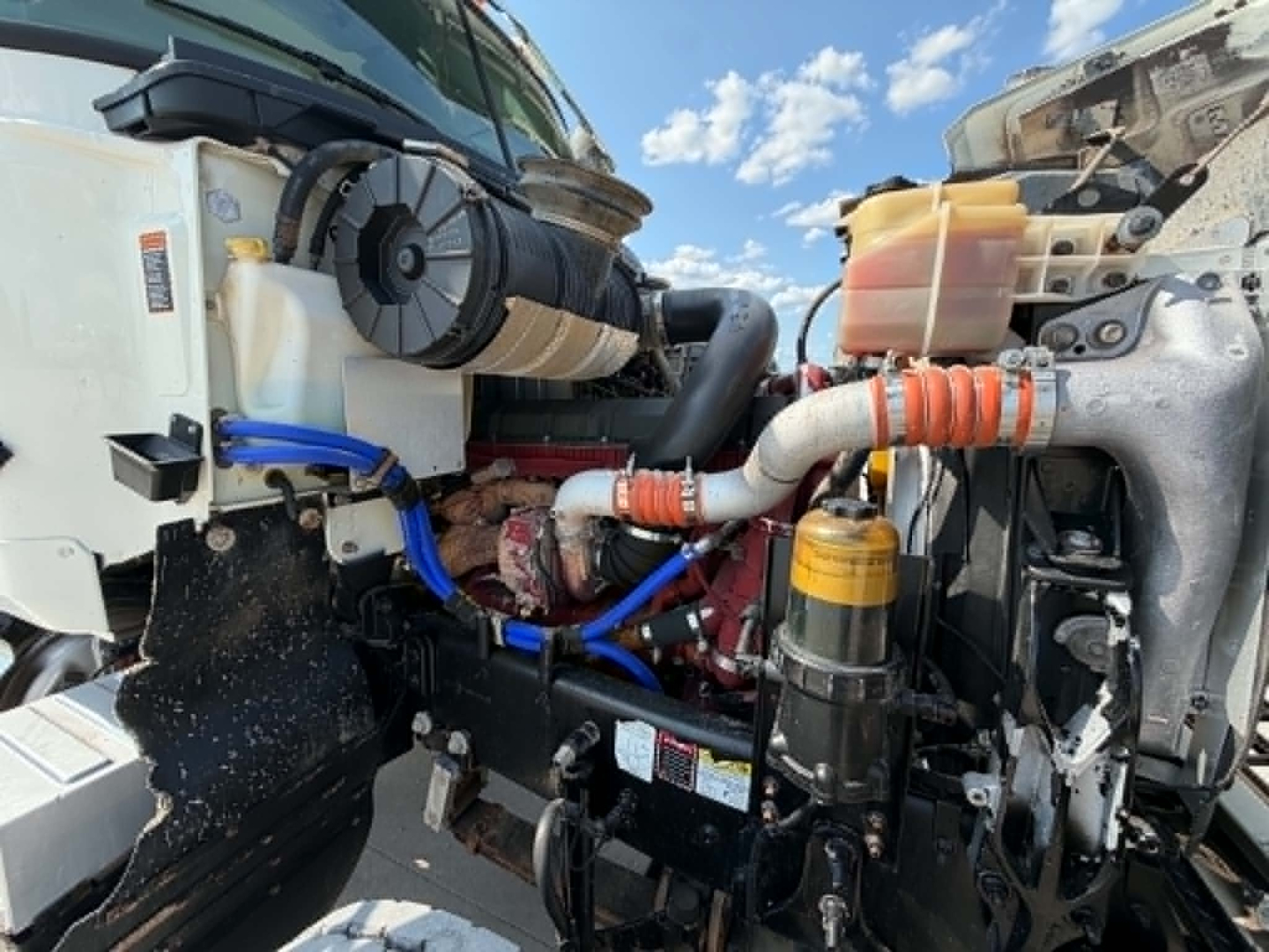 Engine bay of a 2019 Mack CHU613 showing coolant reservoir, hoses, and hydraulic lines.