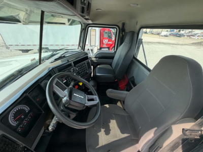 Truck cab interior of a 2019 Mack CHU613 with gray seats, steering wheel, and dashboard; view from passenger seat shows instrument cluster and window.