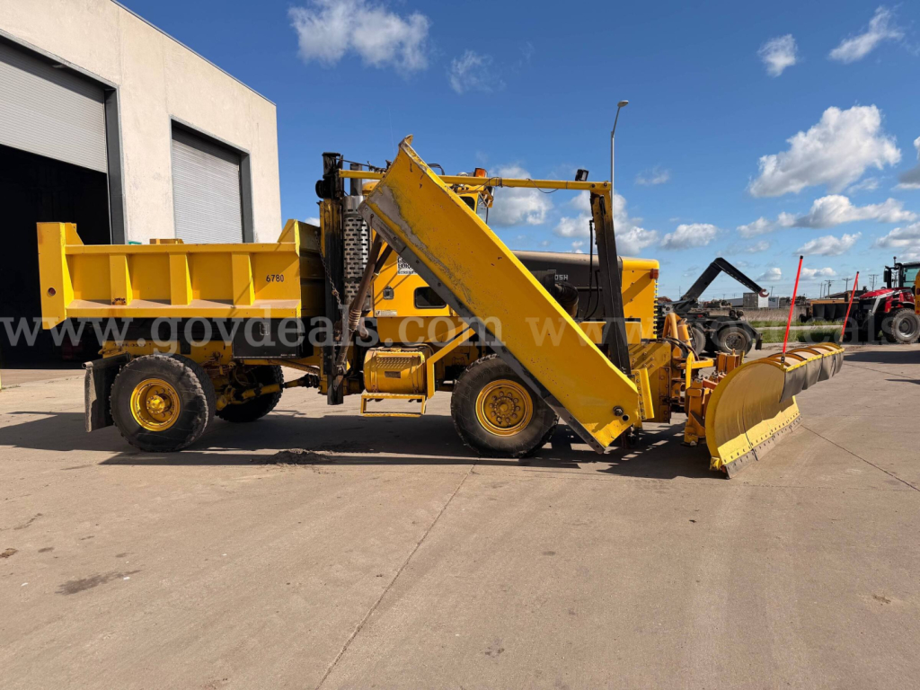 Oshkosh PA-2323-SP snow plow truck side view showing yellow dump bed, hydraulic lift, and front blade.