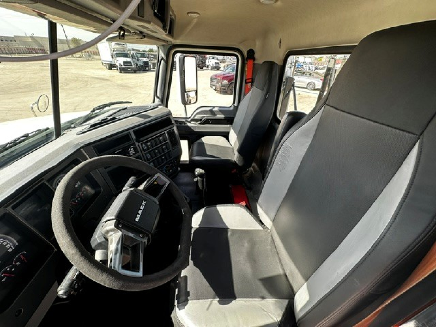 Cab interior of a 2020 Mack PI64T conventional daycab showing steering wheel dashboard and driver seat with grey and black upholstery.