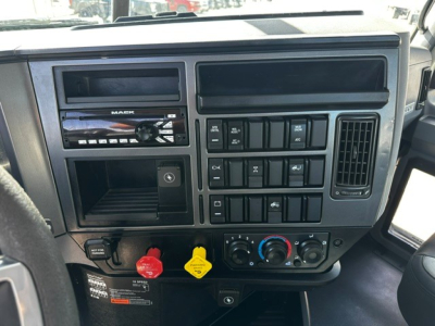 Mack PI64T truck dashboard center console showing stereo, climate controls, and various switches with red and yellow warning caps.