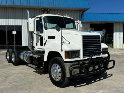 Truck front view of a white 2020 Mack PI64T conventional daycab with chrome bumper guard, dual rear axles, and large grille; no visible text on the vehicle panels.