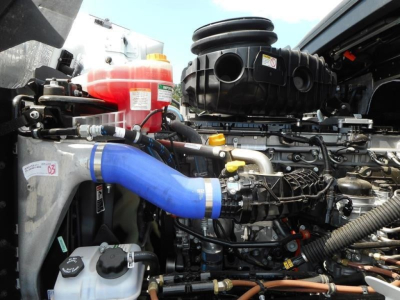 Engine bay of a Western Star 49X truck showing blue silicone intercooler hose, coolant reservoir, and various hoses and components.