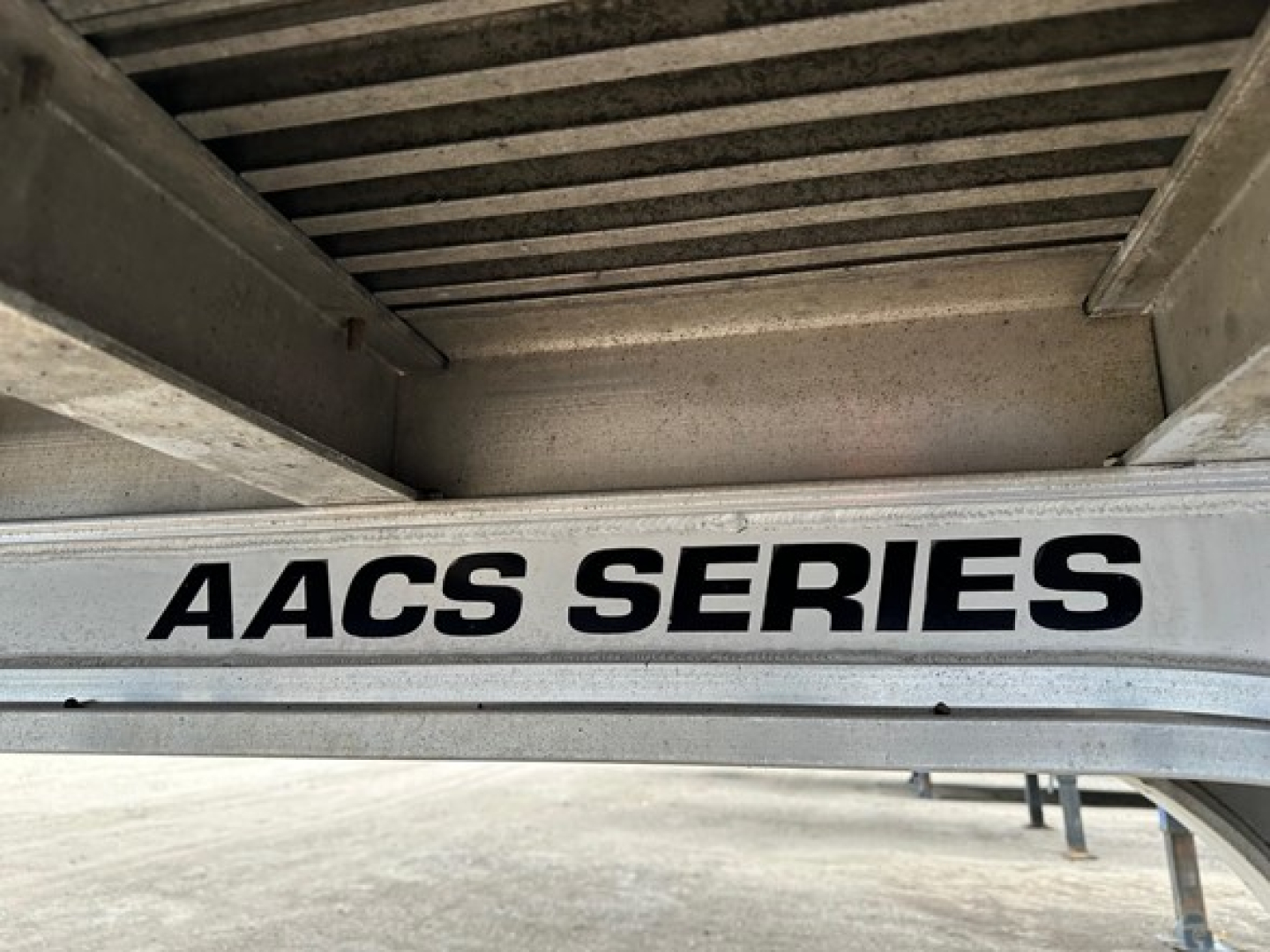 AACS SERIES label on a Trail King Tk drop deck trailer showing steel gray frame and upper deck structure.