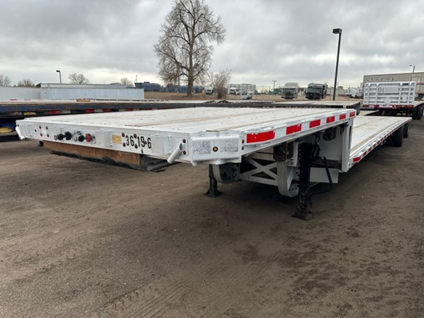 Trailer: 2015 Trail King Tk Drop Deck flatbed trailer with extended drop deck, aluminum deck, side rails, landing gear, and wheel bogies visible.