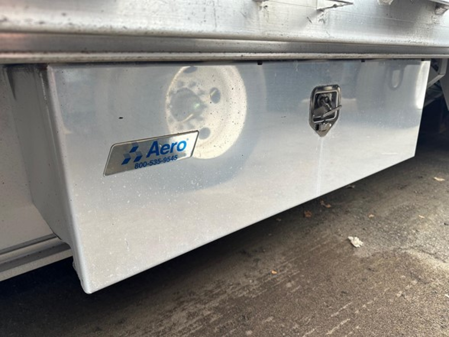 Trailer deck storage box under rear of 2015 Trail King TK Drop Deck trailer showing Aero sticker and latch.