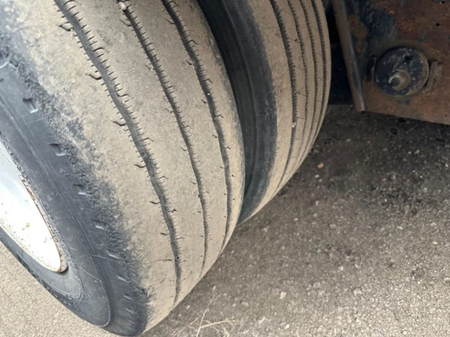 Trailer tire and undercarriage components of a 2015 Trail King TK Drop Deck trailer visible, with treaded dual tires and suspension hardware.