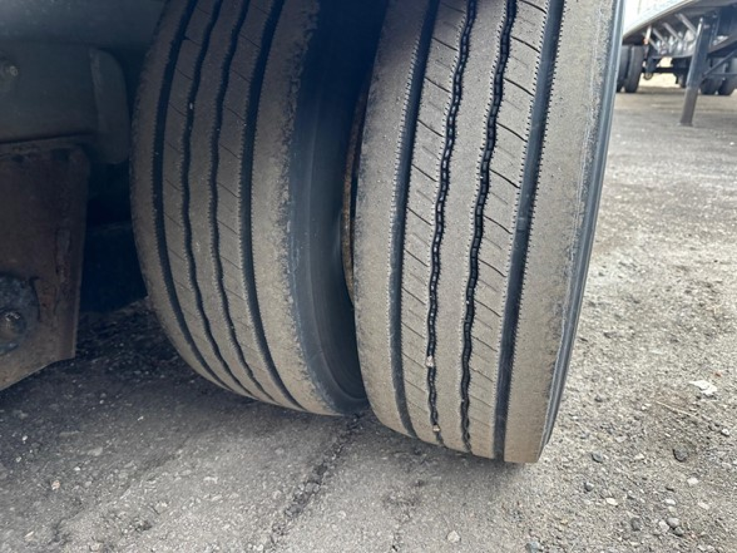 Trailer wheel view showing dual tires with tread and sidewall details on a drop deck trailer.