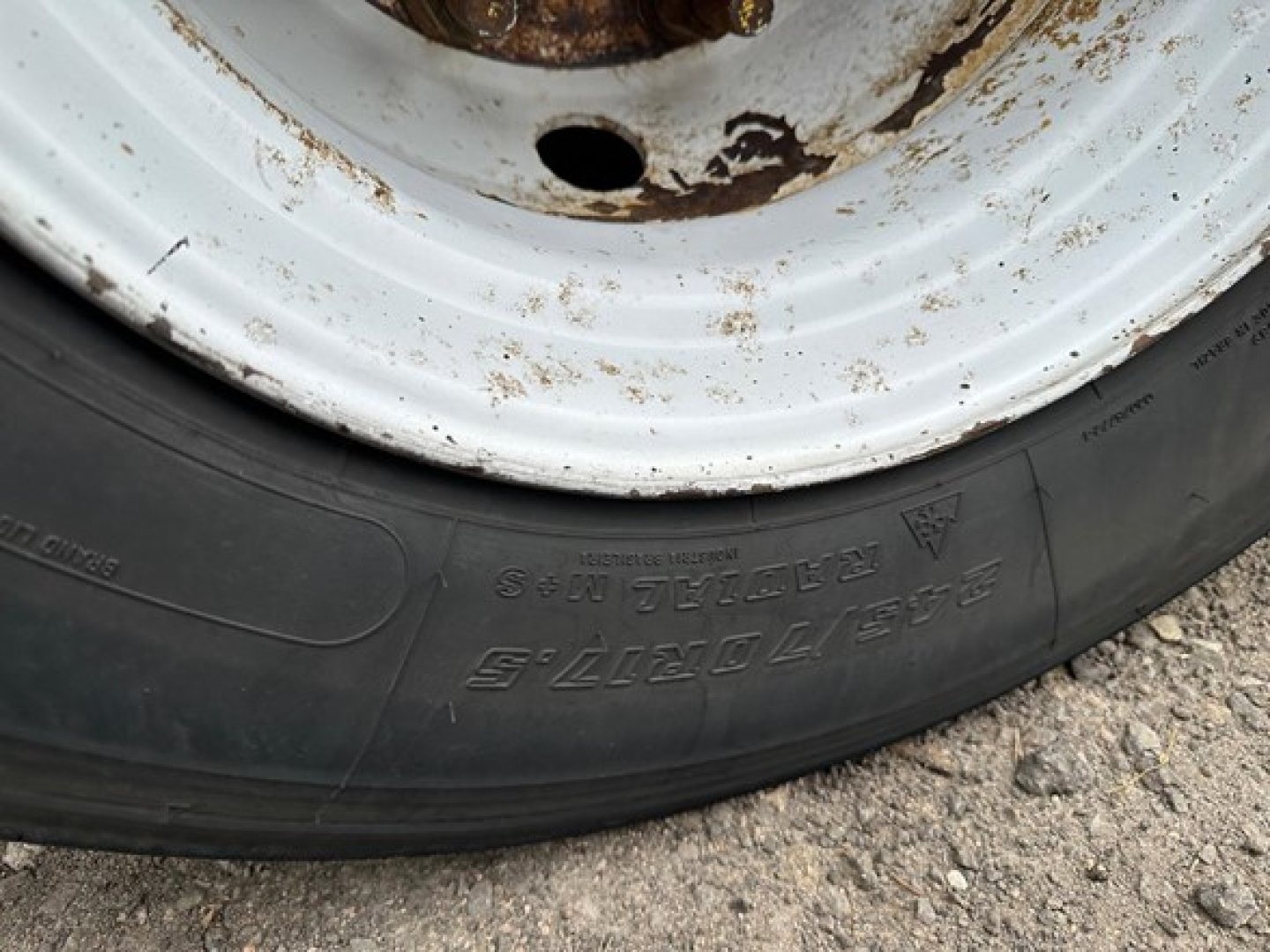 Trailer wheel close-up showing tire with visible markings and white wheel rim.