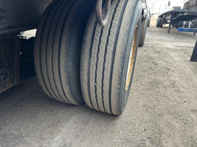 Trailer wheel close-up showing dual rear tires with tread and yellow wheel rims on a Trail King Tk Drop Deck trailer.