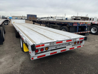 Trailer deck showing aluminum drop deck trailer with dual rear axles and red/white reflective tape.