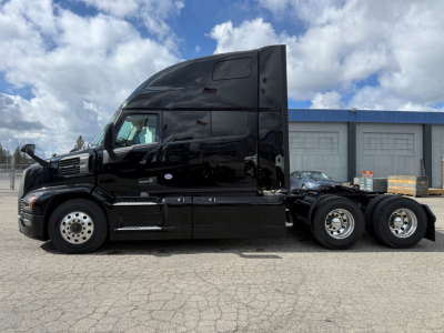 Truck side view showing a black 6x4 semi tractor with sleeper cab, chrome wheels, three rear axles, no visible text.