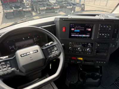 Mack PR64T76H truck cab interior showing steering wheel and dashboard with touchscreen display and controls.