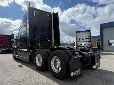 Mack PR64T76H conventional sleeper truck rear view showing dual rear axles and fifth wheel with mud flaps and chrome wheels.