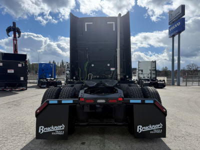Truck chassis view from rear showing fifth wheel, rear mud flaps with Bruchner logo, and blue warning striping.