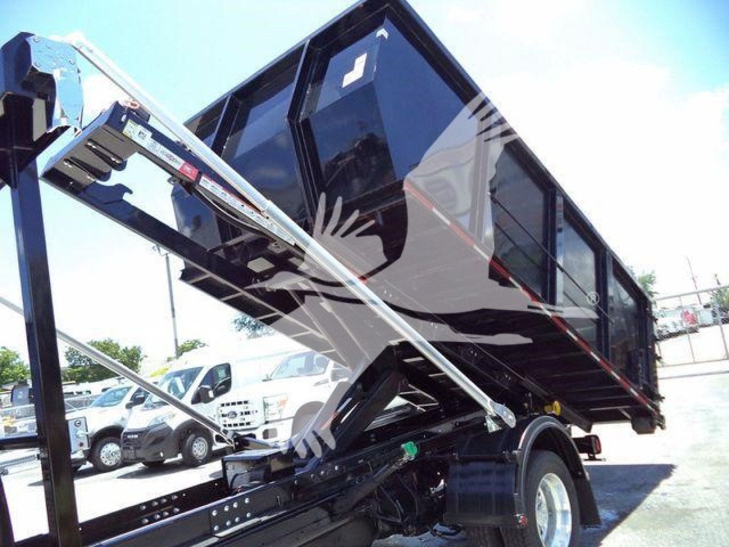 Ram 5500 truck with rolloff dump body and hydraulic hoist in service bay showing cargo bed and wheel.