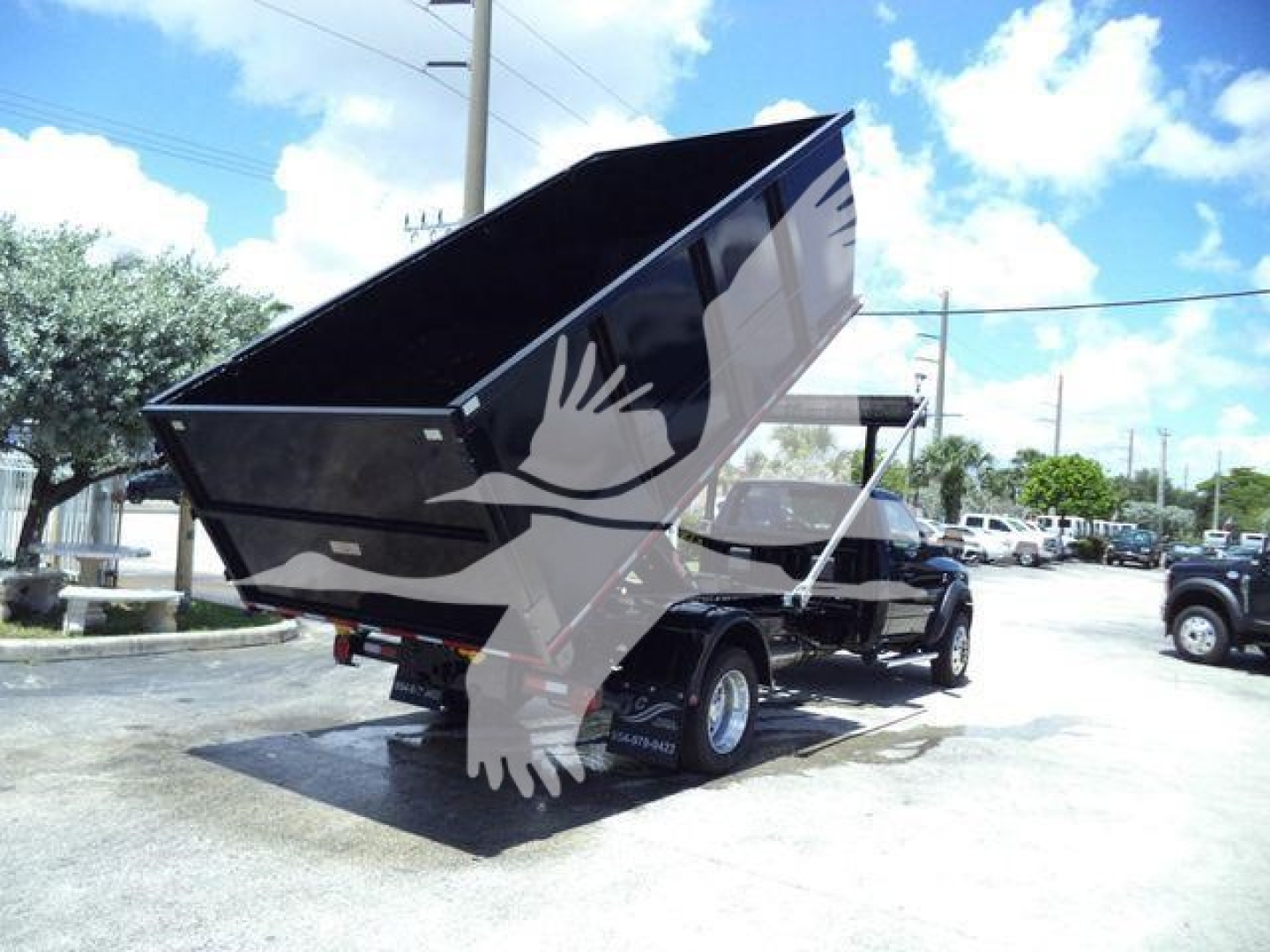 Ram 5500 SLT dump truck in service position rear view showing dump bed raised with black exterior and white graphic eagle decal.
