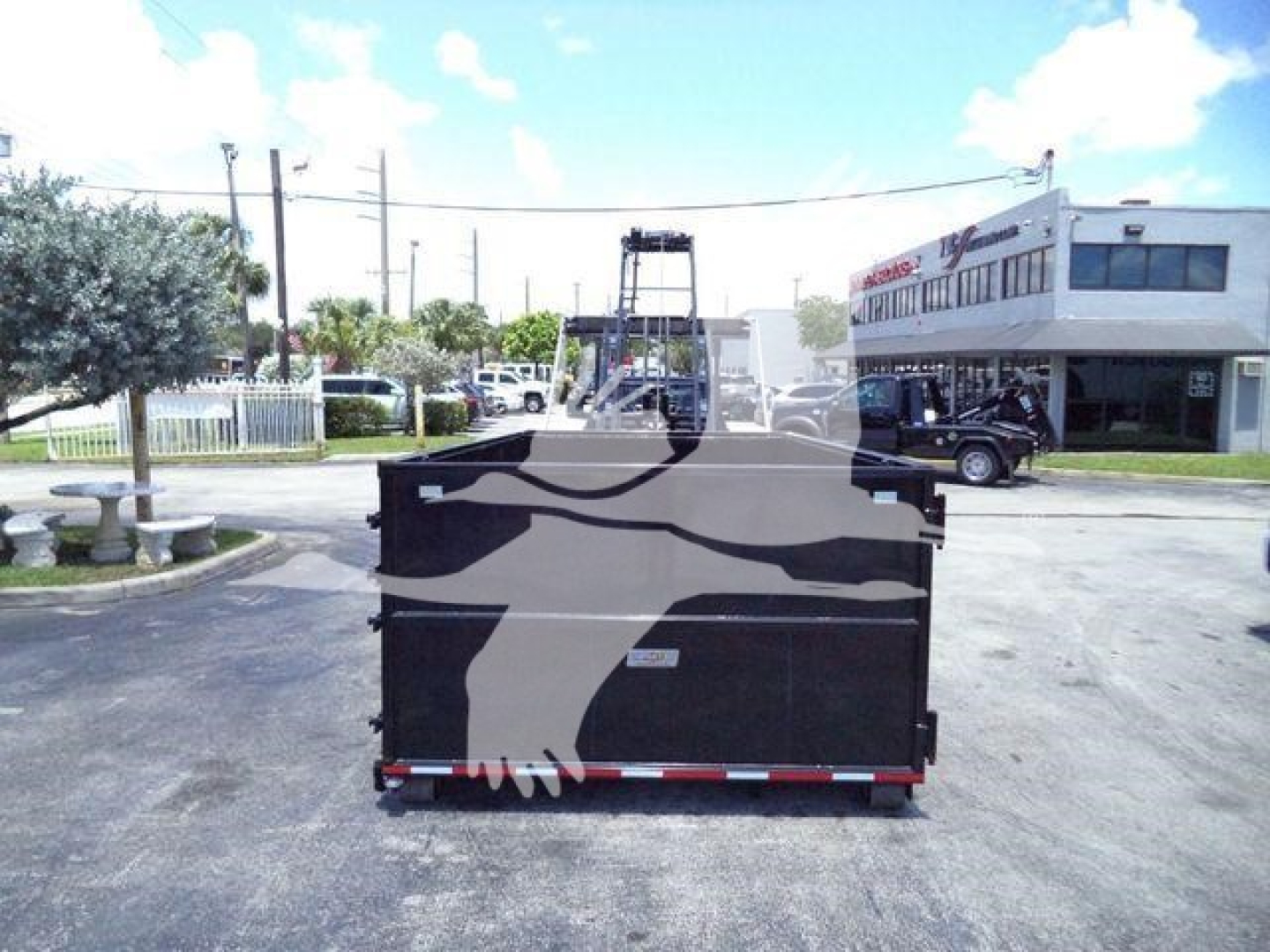 Ram 5500 SLT dump bed view from rear showing cargo bed and hitch, with dealership building and clear sky in background.