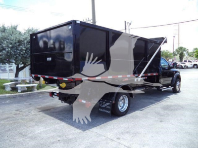 2024 Ram 5500 SLT rolloff truck with black dump body and crane hook, side view showing rear wheels, rear bumper, and reflective tape.