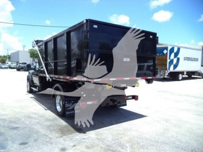 Truck bed with roll-off dumpster container mounted on a Ram 5500 SLT truck. Side and rear views show black container, dual rear wheels, and reflective striping.