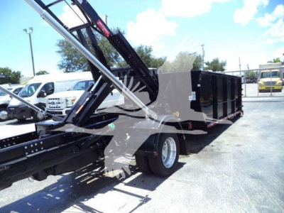 Ram 5500 dump body truck with hydraulic crane in a lot; no visible text legible on the body due to glare