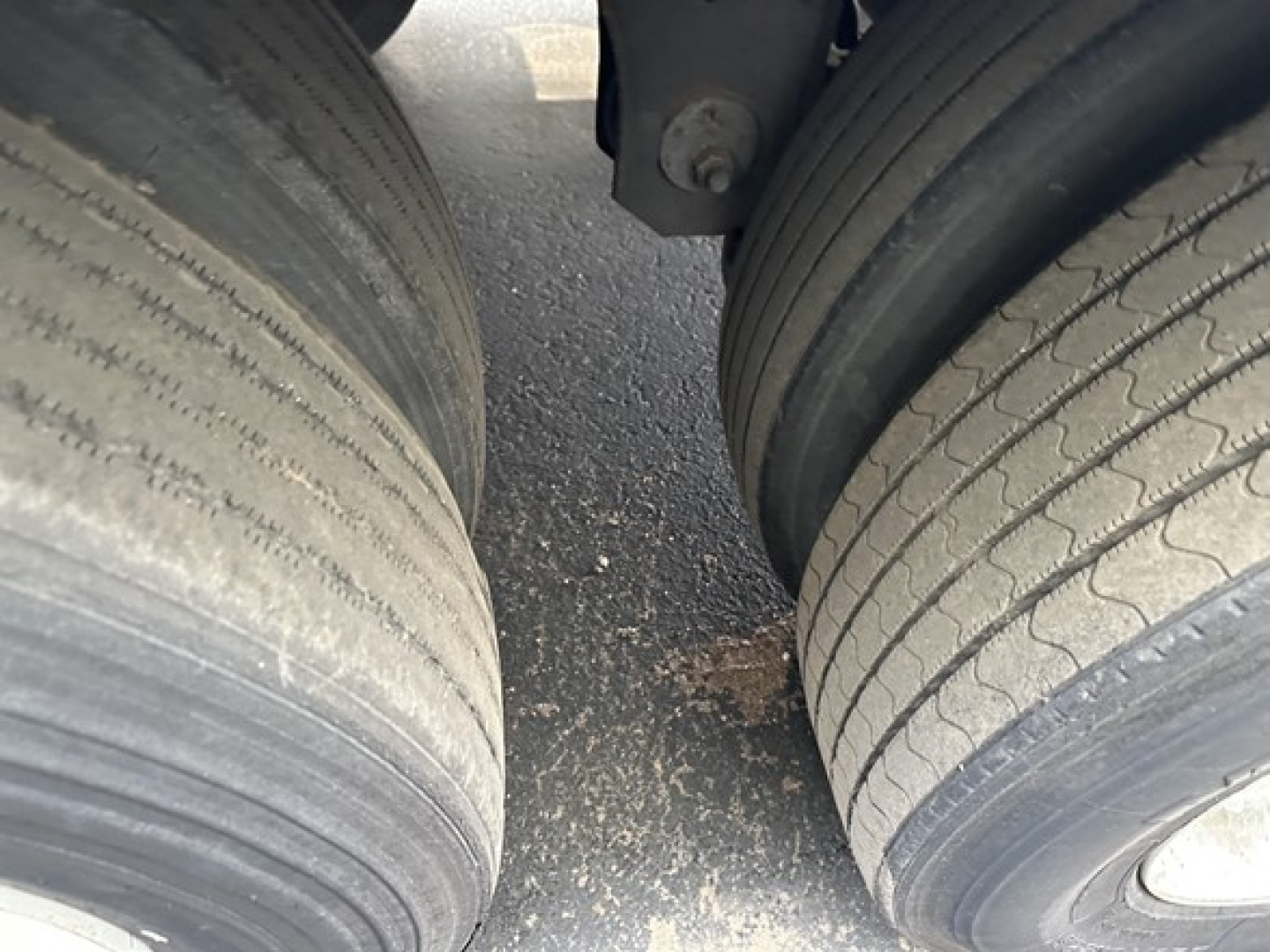 Trailer dual tires with worn tread and dirt between axles under Great Dane S-600 trailer (rear view).
