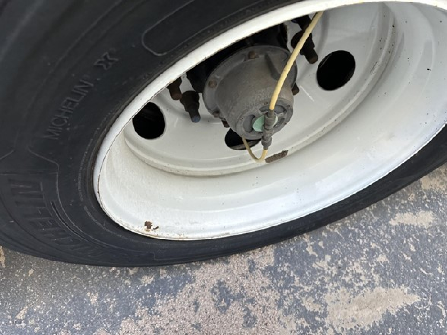 Trailer wheel and hub with white rim showing valve and brake drum, close view.