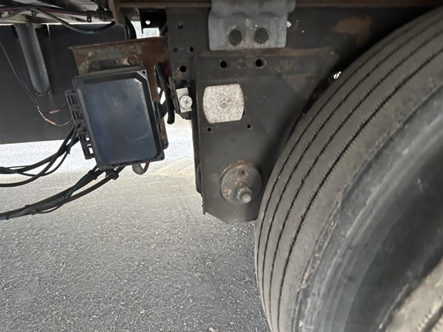 Trailer side showing a maintenance device mounted near the frame and a tire; electronics module with a display and wiring harness visible.