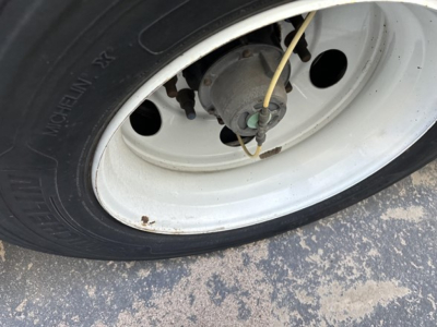 Trailer wheel and hub with white rim showing valve and brake drum, close view.