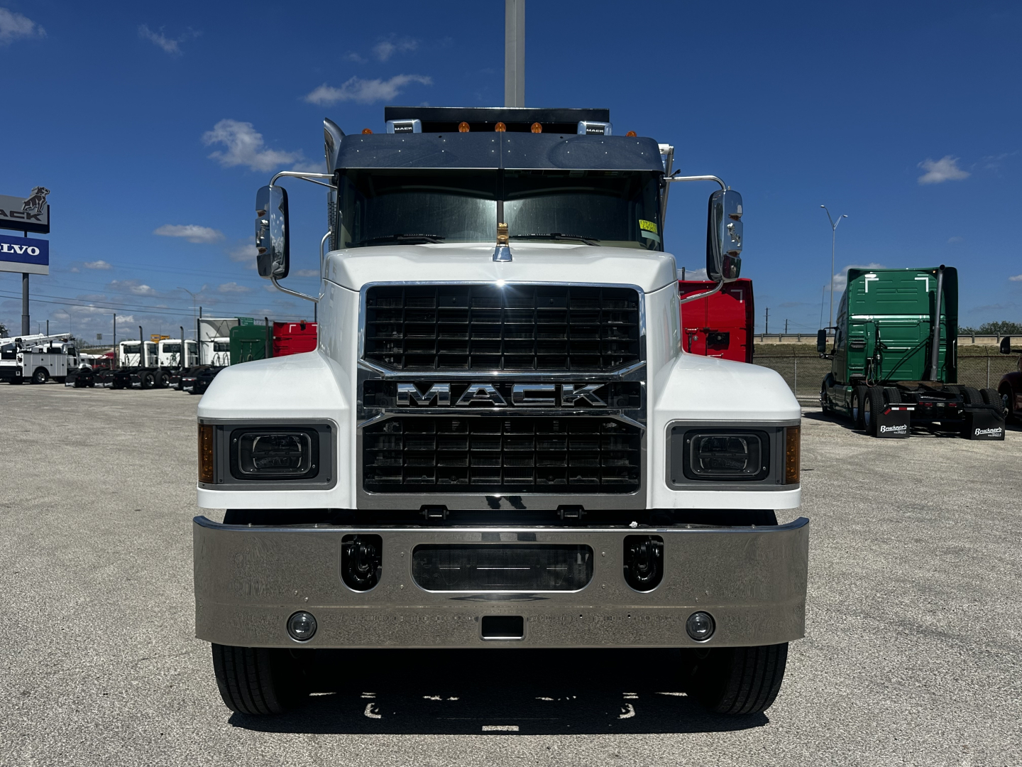 Mack PI64 front view showing grille, bumper, and headlights in showroom lot.