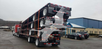 Trailer deck stacked with multiple wheels on a Transcraft DTL-2100 lowboy trailer showing rear ramps and tandem axles.