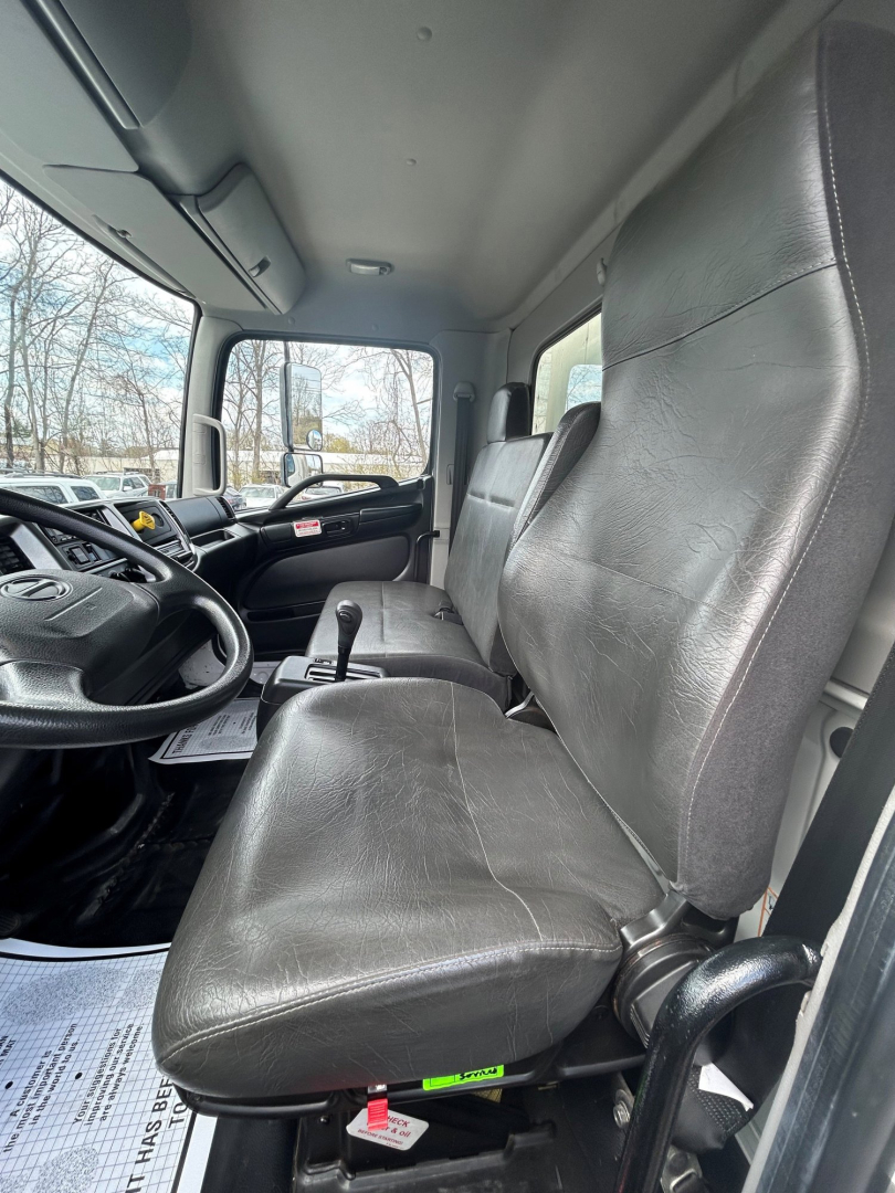 Truck cab interior of a 2020 Hino 338 showing black vinyl seats and driver controls from the passenger side door view.
