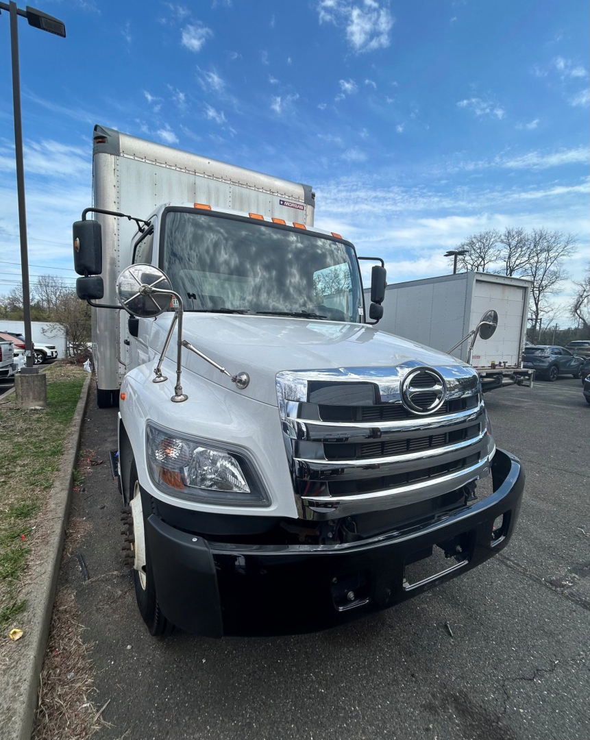 Front view of a white 2020 Hino 338 box truck showing chrome grille, Hino emblem, large side mirrors, and cargo box in background.