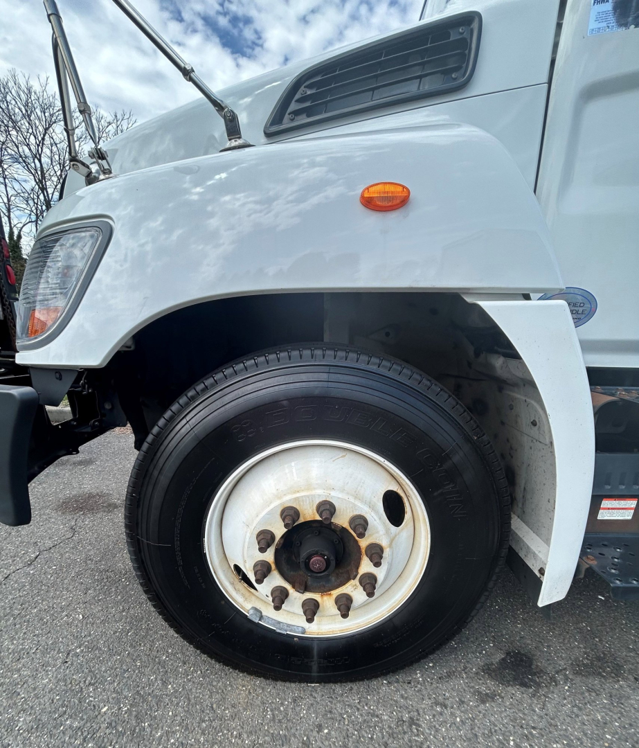 Front wheel area of a 2020 Hino 338 box van truck showing front fender, wheel, and side vent.