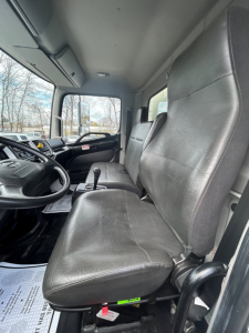 Truck cab interior of a 2020 Hino 338 showing black vinyl seats and driver controls from the passenger side door view.