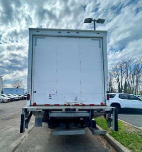 Rear view of a 2020 Hino 338 box truck with a tall white cargo door, rear bumper, and undercarriage visible.