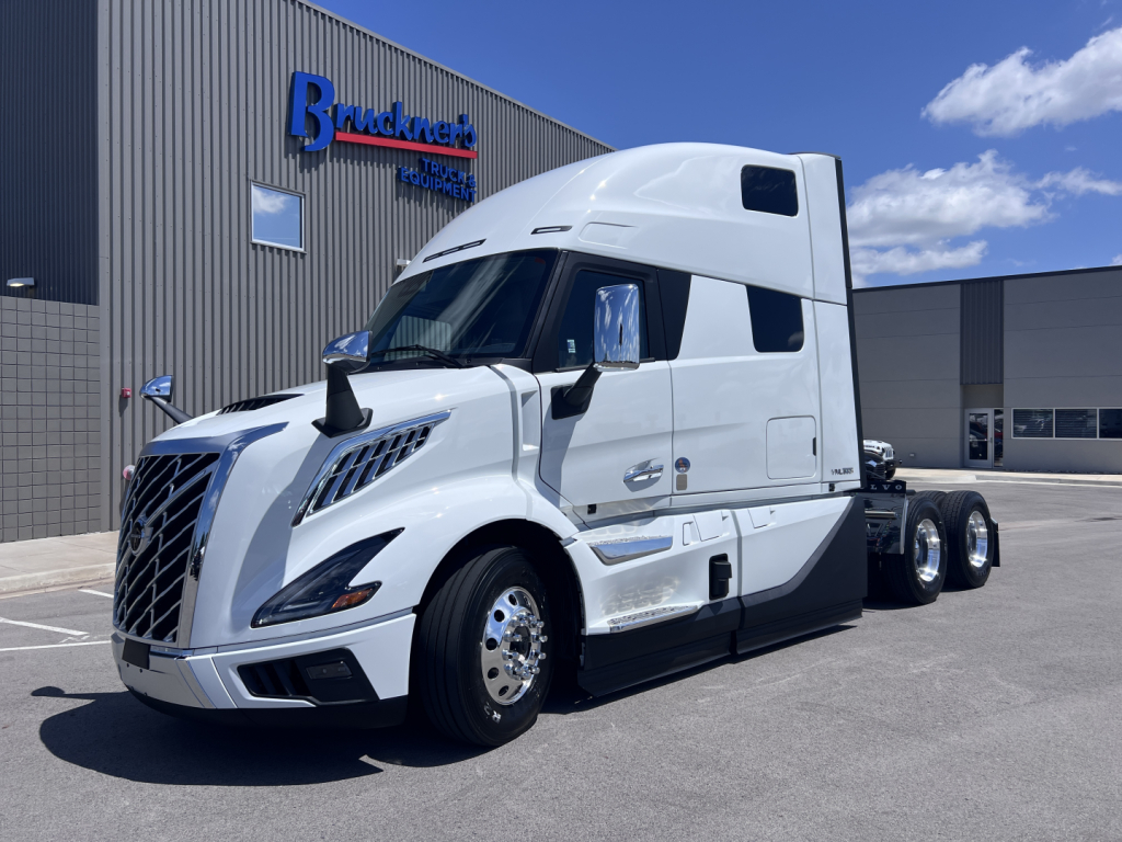 Volvo VNL64T860 tractor-trailer in white, front three-quarter view, parked outside dealership with 'Truck Center' signage in background.