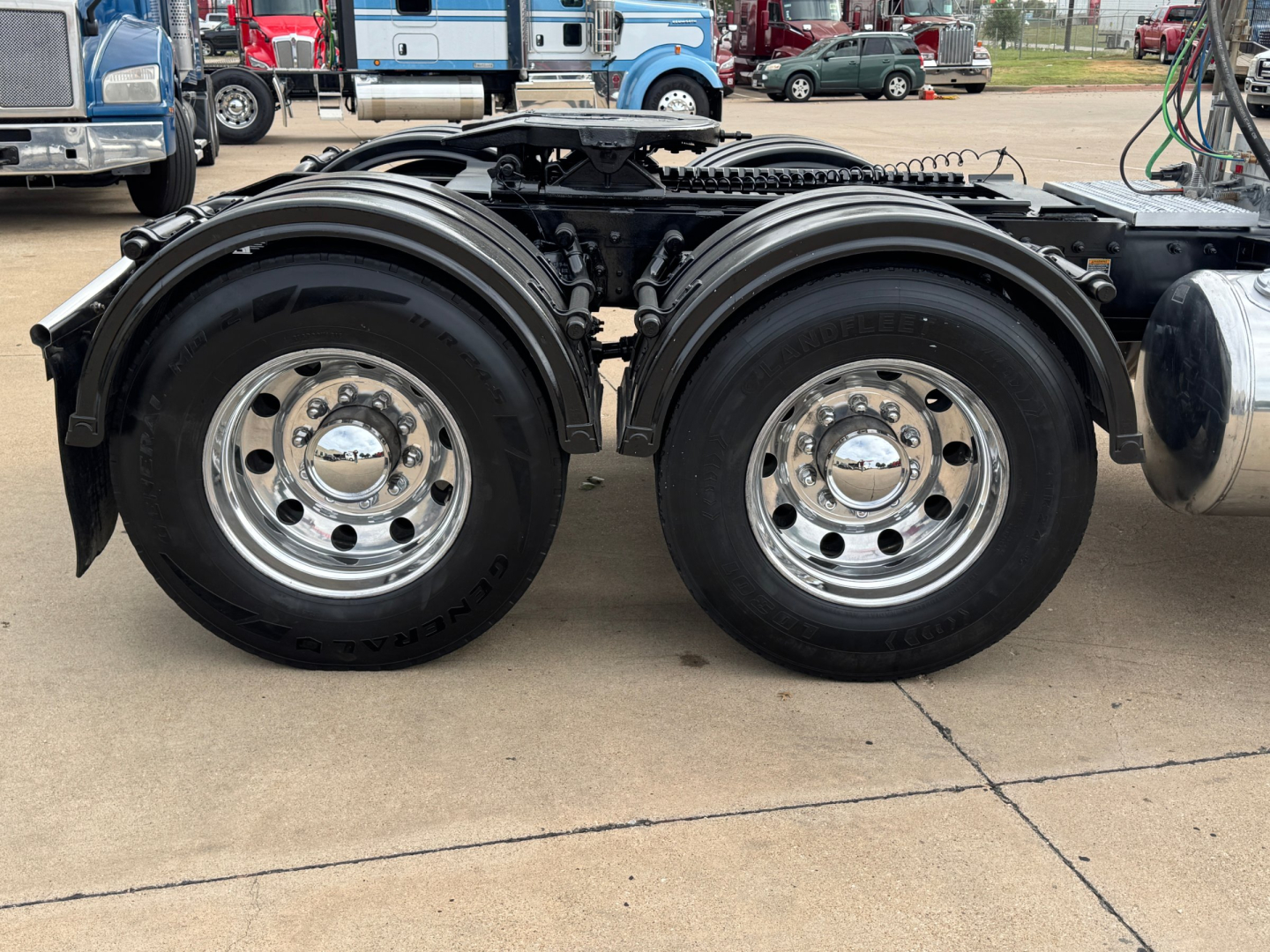 Peterbilt 389 tractor dual rear axles with chrome wheels and black fenders, side view showing rear wheel assembly and frame.