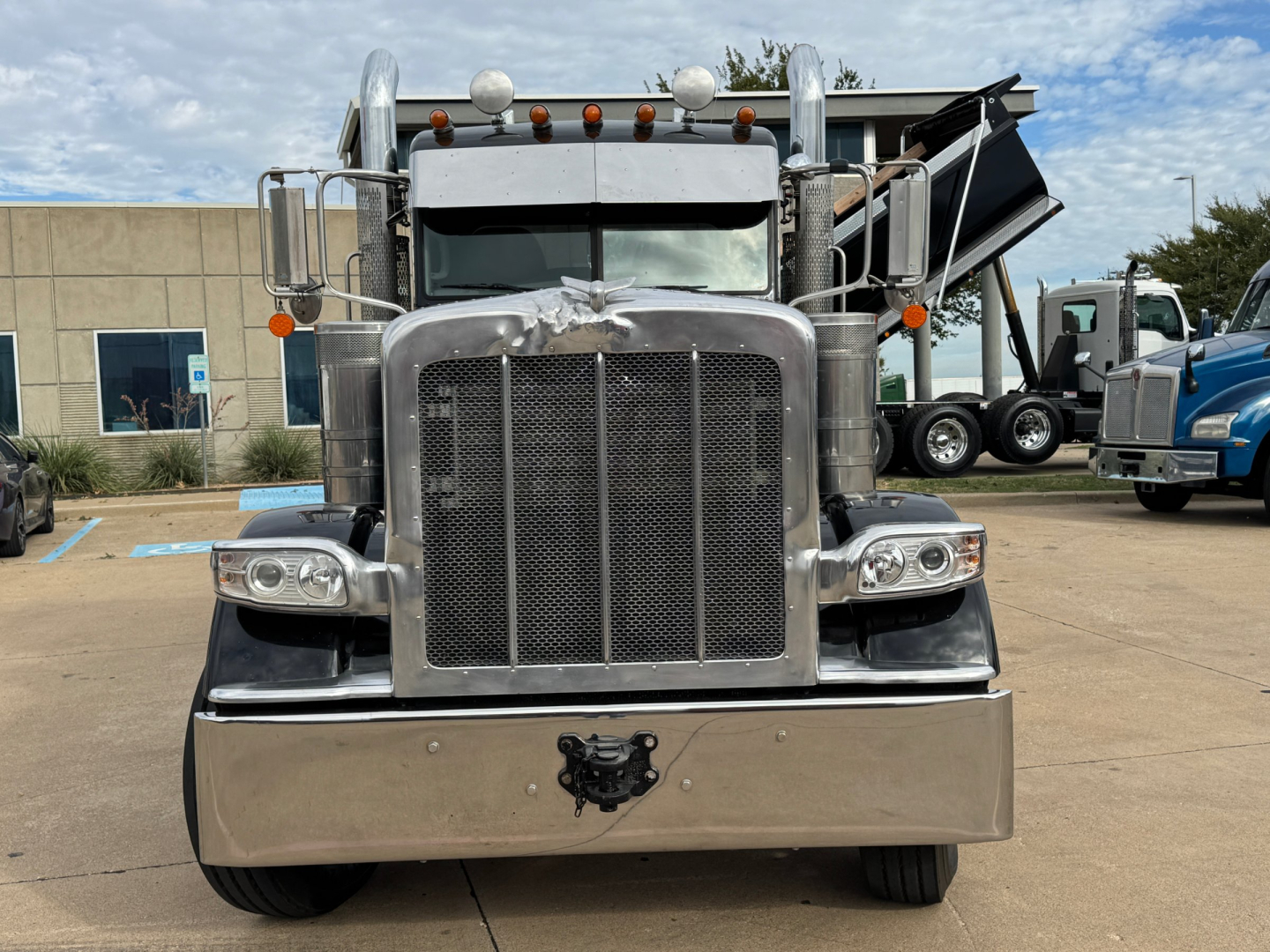 Peterbilt 389 conventional daycab truck front view showing large chrome grille, bumper, dual headlights, and mirrors.