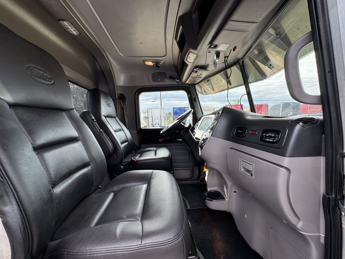 Peterbilt 389 truck cab interior showing black leather seats and dashboard with steering wheel, VIN and stock not visible.