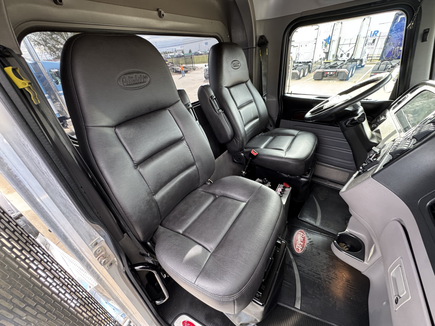 Peterbilt 389 interior cabin showing driver and passenger seats with steering wheel and dashboard visible.